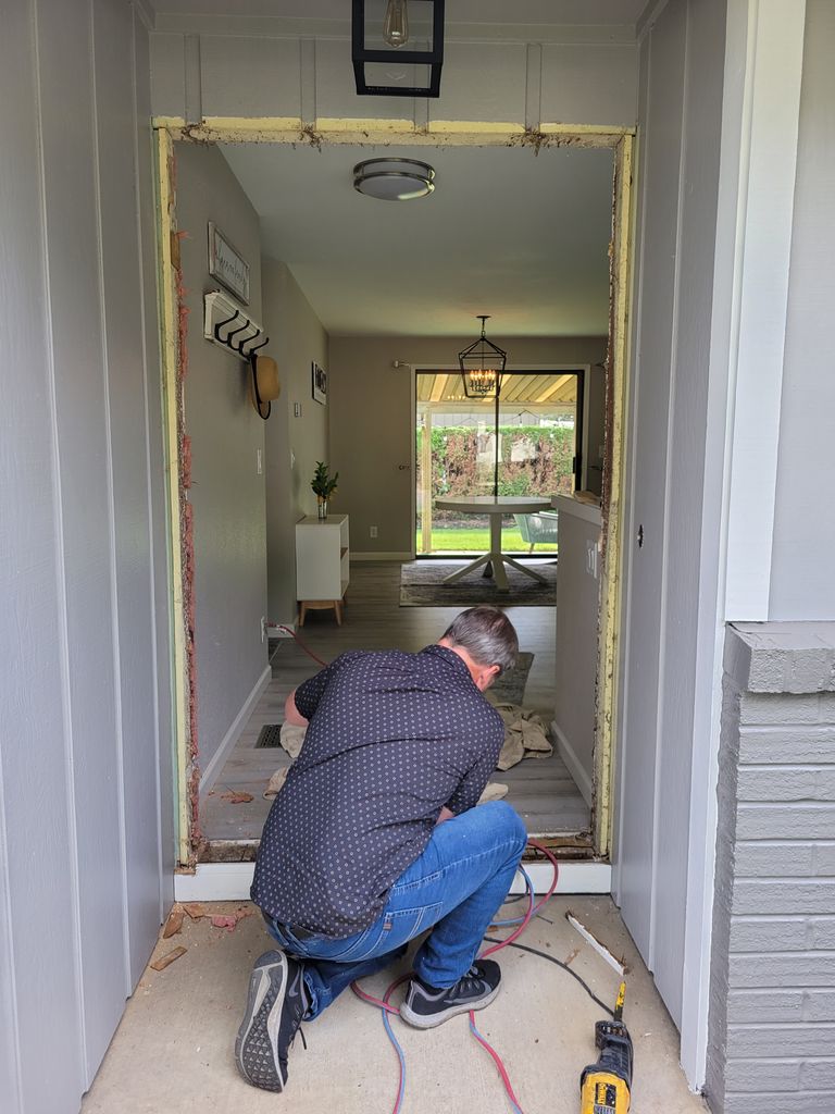 Person crouched in doorway to install a new door.